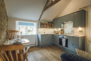 a kitchen with blue cabinets and a table in a room at The Barrington Boar in Ilminster