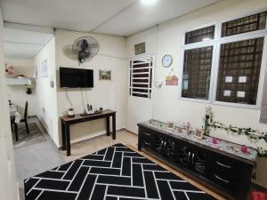 un soggiorno con tappeto bianco e nero e TV di Sri MaLati Homestay and Event Space a Balik Pulau