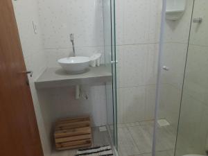 um banheiro com pia e box de vidro em Pousada Maria de Lino em São Sebastião