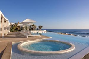 a large swimming pool next to the ocean at Stylish Oceanfront Condo with Panoramic Views in El Pescadero