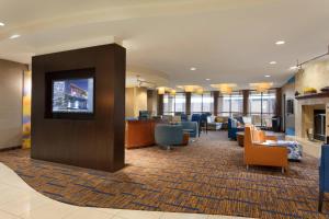 a lobby with a waiting area with chairs and a tv at Courtyard by Marriott Oklahoma City North/Quail Springs in The Village