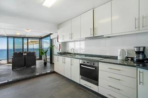 cocina con armarios blancos y vistas al océano en The Wave House - Seaside Haven, en Jardim do Mar