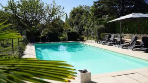 een zwembad met ligstoelen en een parasol bij Gîte Du Pré Pommier - Clim - Piscine - Sauna in Azé