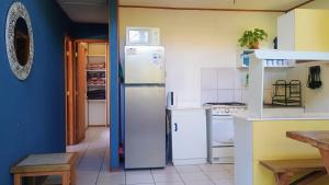 a kitchen with white appliances and a blue wall at Cabaña Los Laureles in Maitencillo