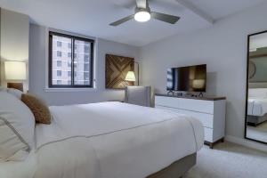 een witte slaapkamer met een groot bed en een spiegel bij Sojourn Courtland Towers 2 BR in Arlington