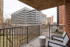 een balkon met 2 stoelen en een hoog gebouw bij Sojourn Courtland Towers 2 BR in Arlington