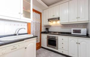 a kitchen with white cabinets and a sink and a microwave at Gorgeous Apartment In Santa Pola in Santa Pola