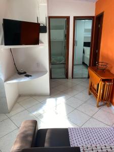 un soggiorno con un divano e una televisione di Host dos Anjos II ad Arraial do Cabo