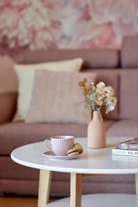 a coffee table with a cup and a vase with flowers at Boszkowo Horizon Park Apartament 27 "Romantic" in Boszkowo
