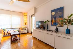Una sala de estar con televisión y un sofá. en TrendyHomes Retamar III - Playa, piscina y golf, en Almería