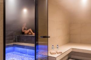 a woman sitting on the ledge of a shower at Hôtel Saint Charles Val Cenis in Lanslebourg-Mont-Cenis