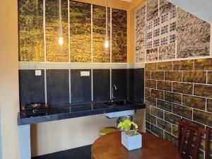 cocina con armarios negros y mesa de madera en Liyans Eco Villa, en Habaraduwa Central