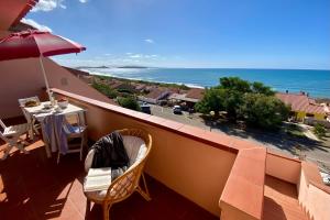 a balcony with a table and an umbrella and the ocean at Bellavista in Funtana Meiga