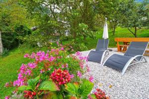 two chairs and a bench in a garden with flowers at Apartments Laznica in Cerkno