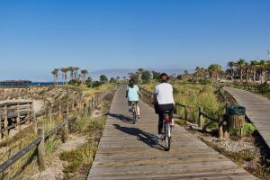 Dos personas montando en bicicleta en un paseo marítimo en la playa en TrendyHomes Retamar III - Playa, piscina y golf, en Almería