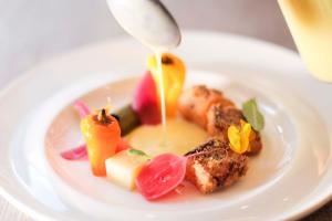 a white plate with food on a table at Hotel Ristorante Al Caminetto WorldHotels Crafted Adults Only in Torri del Benaco +125 photos