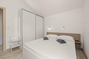 a bedroom with a white bed with two towels on it at Apartments Jana & Paula in Cres +23 photos