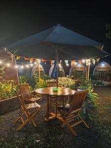 a table with chairs and an umbrella in front of a building at Indah Damai Cottages in Sidomukti