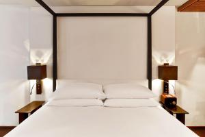 a bedroom with a white bed with two lamps at Le Metropolitan, Paris Tour Eiffel, a Tribute Portfolio Hotel in Paris