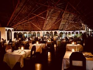 a restaurant with white tables and people sitting at tables at Blue Bay Village in Watamu