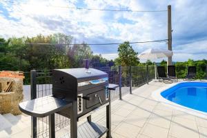 een barbecue naast een zwembad bij Apartment Lara with Swimming Pool - Paradiz in Veli Turini