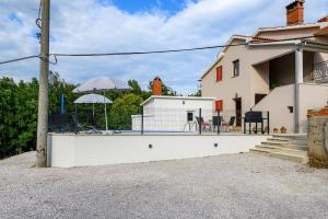 een wit huis met stoelen en een parasol bij Apartment Lara with Swimming Pool - Paradiz in Veli Turini