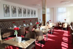 ein Esszimmer mit Tischen, Stühlen und Blumen in der Unterkunft Flora-Apart-Residenz in Fredersdorf