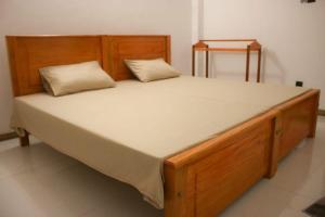 a large wooden bed with two pillows on it at River's Edge Resort Sinharaja in Kudawe