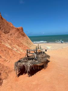 a bench sitting on a beach next to the ocean at Hostel Flor da Vida in Canoa Quebrada