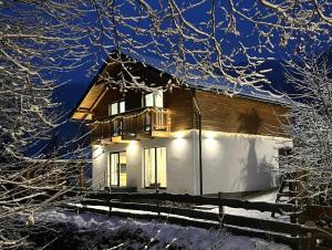 a house with a balcony in the snow at night at Resort Biela Skala - CHALET Chopok Jasná Juh in Bystrá