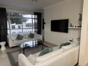 a living room with two white couches and a flat screen tv at Stadium Apartment in Cape Town
