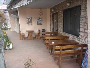 une rangée de tables et de bancs en bois à l'extérieur d'un bâtiment dans l'établissement Hotel I Cugini, à Castelfidardo