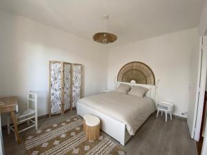 a bedroom with a white bed and a table and a desk at La Maison du Lavoir in Port-en-Bessin-Huppain