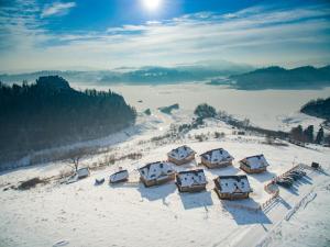 um grupo de cabanas no topo de uma montanha coberta de neve em Osada Cztery Pory Roku Czorsztyn em Czorsztyn