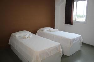 two beds with white sheets in a room with a window at Hotel Centro Fashion in Fortaleza