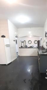 a kitchen with white walls and a white refrigerator at Casa da praia, Caraguatatuba in Caraguatatuba