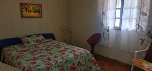 a bedroom with a bed with a flowered blanket and a window at Casa da Acerola in Rio das Ostras
