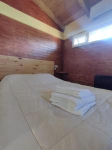 une chambre avec un lit avec des serviettes blanches dessus dans l'établissement Anlupa Departamento, à El Bolsón