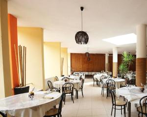 Un comedor con mesas y sillas blancas. en Villaggio Marbella Club, en Palinuro