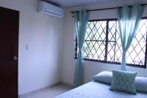 カリにあるCasa Esperanzaのベッドと青いカーテンの窓がある寝室