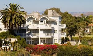 a large white house with a palm tree and flowers at Blue Lantern Inn, A Four Sisters Inn in Dana Point