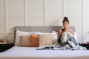 una mujer sentada en una cama debajo de una manta en VIDA by Elegant Hospitality - near malls, en El Cairo