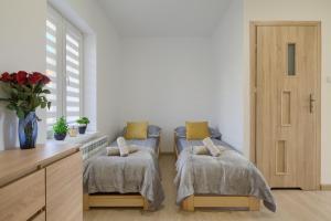 ティリチにあるApartamenty Tylicka Ostojaのベッドルーム1室(ベッド2台、花瓶付きのデスク付)