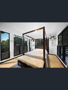 a bedroom with a canopy bed and windows at Rakali Retreat in Cooran