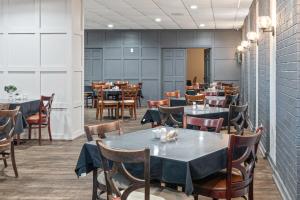 a restaurant with tables and chairs in a room at Plantation Inn in Houma