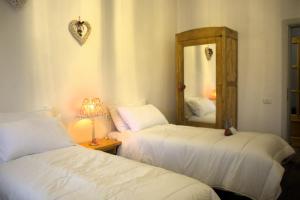 two beds in a room with a mirror and a lamp at Lodge Pizzo Alpestre in Abetone