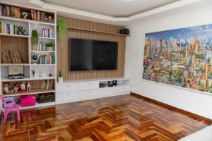een woonkamer met een flatscreen-tv aan de muur bij Casa Enorme com Piscina, Sauna e Área para Festas in Belo Horizonte