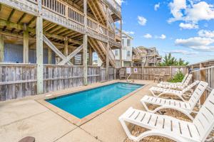 a swimming pool with two lounge chairs next to a building at Storm's End in Waves