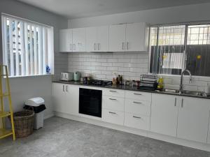 a kitchen with white cabinets and a sink at CozyHomes Woolloongabba B&B in Brisbane
