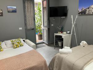 een slaapkamer met twee bedden en een tv aan de muur bij Alle porte del Castello 23 in Catania